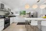 Kitchen featuring white flat-panel cabinetry, stainless steel appliances, a tile backsplash, and a central island with a solid-surface countertop