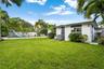 Expansive backyard featuring a rectangular swimming pool with a slide, masonry perimeter wall, mature palm trees, and manicured lawn