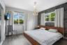Wood-finish flooring, accent wall with patterned wall covering, multi-light pendant fixture, and large windows