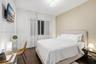 Room featuring dark wood-finish flooring, neutral-toned accent wall, and a central ceiling-mounted drum light fixture