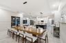 Open concept kitchen and dining area featuring large format tile flooring, a central kitchen island with contrasting cabinetry, white shaker-style wal
