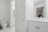 Bathroom featuring a white vanity cabinet with a stone-top integrated sink, a full-height wall mirror, a polished chrome faucet, and a standard-height