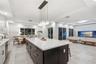 Kitchen featuring a center island with contrasting cabinetry, stone-finish countertops, tile flooring, built-in media console, and multi-pendant light