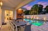 Covered patio with paver flooring, horizontal slat wood accent wall, built-in shelving, swimming pool with integrated spa, and vertical privacy fencin