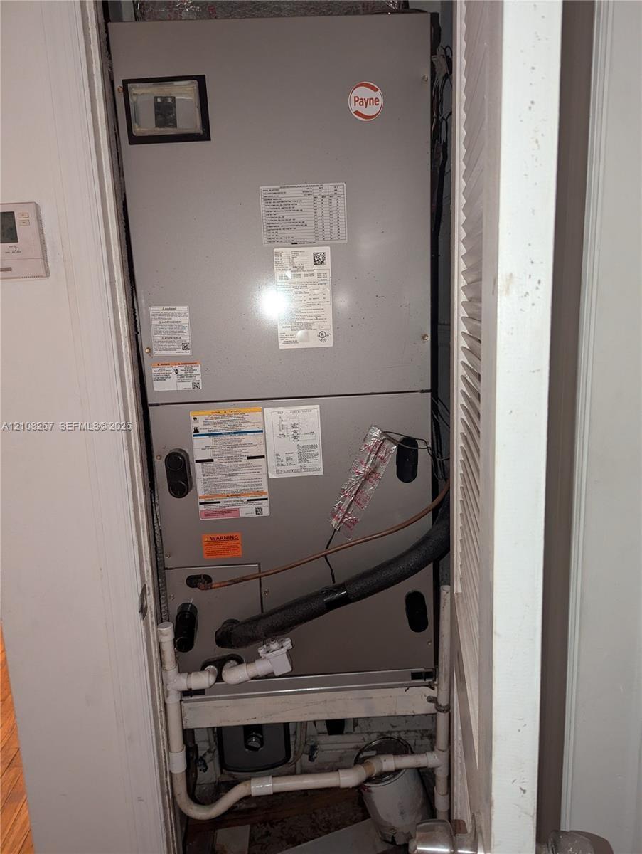 Payne furnace unit featuring a metal enclosure with built-in plumbing connections and a mounted digital thermostat