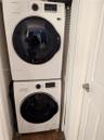Stacked white front-load washer and dryer unit, louvered closet door, and interior door with brushed nickel hardware