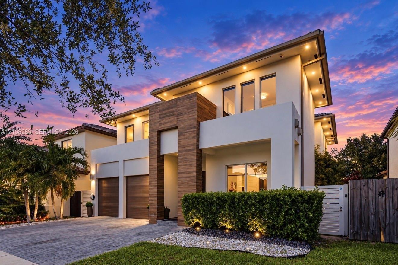 Contemporary exterior featuring smooth stucco finish, vertical wood-paneling accents, recessed soffit lighting, two-car garage with wood-finish doors,