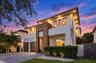 Contemporary exterior featuring smooth stucco finish, vertical wood-paneling accents, recessed soffit lighting, two-car garage with wood-finish doors,