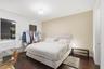 Bedroom featuring wood-finish flooring, two windows, a neutral accent wall, and a central ceiling-mounted light fixture