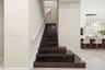 Staircase featuring dark wood-finish treads, white handrail, and white balusters, situated on stone-finish flooring with a multi-pendant light fixture