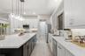 Kitchen featuring a central island with a solid-surface countertop, white shaker-style cabinetry, stainless steel appliances, and multi-light pendant 