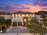 Two-story residence featuring a paved driveway, dual-car garage with wood-finish doors, contemporary tile roof, and textured stone facade accents