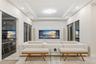 Living space featuring a tray ceiling, recessed lighting, large-format tile flooring, built-in media cabinetry, and multiple sliding glass doors