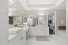 Dual vanity featuring rectangular vessel sinks, white stone countertops, white cabinetry with brushed metallic hardware, and full-width wall mirrors