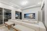 Tray ceiling with integrated geometric lighting, large-format tile flooring, and custom built-in cabinetry featuring recessed media display with wood-