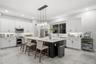 Kitchen featuring white Shaker-style cabinetry, a central island with a contrasting dark base and stone countertop, stainless steel appliances, recess