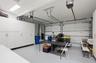 Two-car garage featuring a sealed concrete floor, dual automatic garage door openers, and extensive floor-to-ceiling built-in white cabinetry