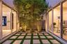 Central atrium featuring large-format concrete pavers, integrated synthetic turf grid, mature bamboo specimens, and expansive floor-to-ceiling sliding