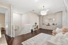 Dark wood-finish flooring, built-in floor-to-ceiling cabinetry with integrated storage, white spindle staircase railing, and a tiered drum pendant lig