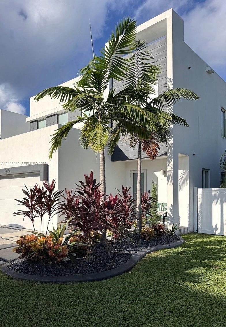 Contemporary two-story exterior featuring a white stucco facade with dark contrasting panels, horizontal sliding windows, and a segmented concrete dri