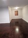 Interior space featuring dark wood-finish flooring, crown molding, and a single window with slatted blinds