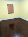 Interior room featuring dark-stained wood-finish flooring, light-colored walls, crown molding, and a recessed window with horizontal blinds