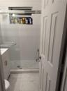 Bathroom featuring a walk-in shower with a glass enclosure, built-in tiled niche, stone-patterned floor tiling, and a vanity with a white cabinet