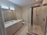Bathroom featuring a long vanity with stone-style countertop and integrated sink, full-width mirror, glass-enclosed shower with tiled surround, and ce