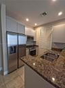 Kitchen featuring flat-panel cabinetry, stone countertops, stainless steel appliances, double-basin sink with a gooseneck faucet, and tile flooring