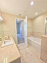 Bathroom featuring a rectangular undermount sink, stone-finish countertop, tile flooring, and a tiled soaking tub surround