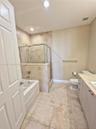 Bathroom featuring a soaking tub, separate glass-enclosed shower with tiled surround, stone-top vanity, and large-format tile flooring