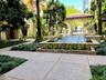 Courtyard featuring a tiered fountain with stone lion sculptures, concrete walkways, mature landscaping, and a covered architectural archway