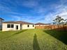 Spacious backyard featuring a grass lawn, perimeter wood fencing, and a stucco exterior with a tiled roof