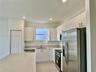 Kitchen featuring white flat-panel cabinetry, stainless steel appliances, a central island with a solid surface countertop, and tile flooring
