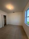 Room featuring neutral-toned tile flooring, light-colored walls, a double-door closet with internal shelving, and a window with a stone sill