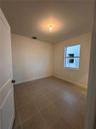 Neutral-toned interior room featuring large-format ceramic tile flooring, a single-hung window, and a crisp white six-panel door