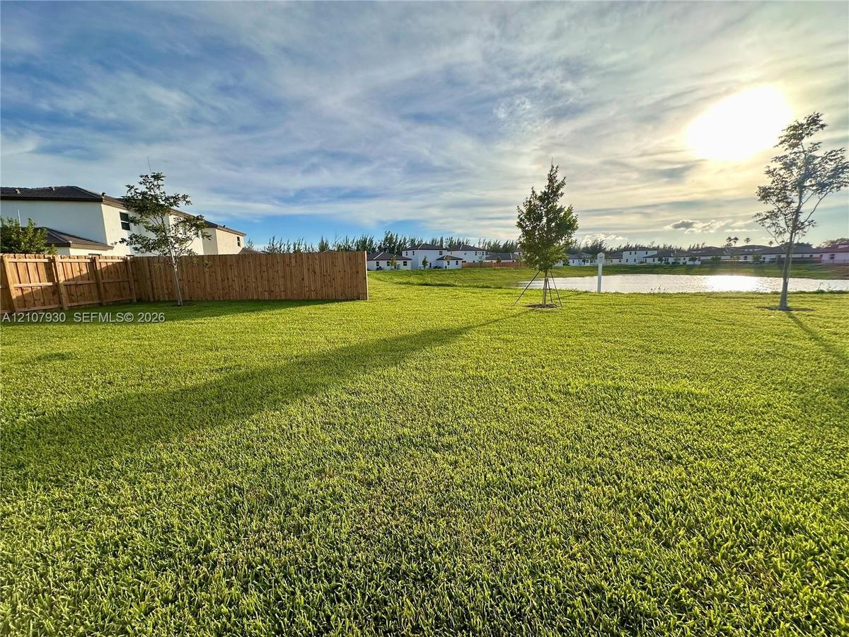 Expansive backyard featuring a large grass lawn, perimeter wood fencing, and waterfront property boundaries