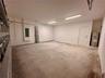 Multi-car garage featuring a concrete floor, dual linear overhead light fixtures, a paneled interior access door, and an integrated water heater