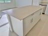 Kitchen island featuring a flat-surface countertop, white cabinetry, satin-finish hardware, and tile flooring