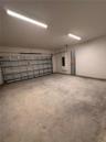 Enclosed two-car garage featuring a sectional metal door, concrete flooring, and linear fluorescent overhead lighting
