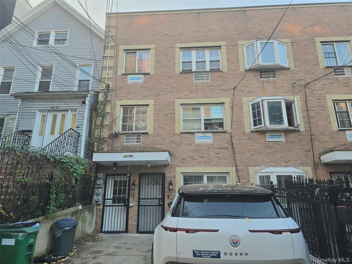 Multi-level brick exterior facade featuring bay windows, stone-trimmed lintels, and metal security doors