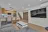 Open-concept kitchen featuring light wood-finish cabinetry, a stone-patterned island countertop, recessed lighting, wood-finish flooring, and a wall-m