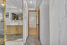 Bathroom featuring large-format wall tiles with veining, wood-finish cabinetry with metallic hardware, recessed lighting, and a gold-trimmed mirror