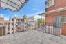 Spacious outdoor terrace featuring tiled flooring, wrought-iron railings, an overhead awning, and exterior brick masonry