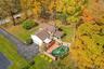 Expansive backyard with a manicured lawn and mature trees,  above ground pool and featuring a multi-level wood deck and a stone chimney