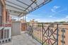 Private balcony featuring a geometric black metal railing, overhead awning, brick facade, and tile flooring