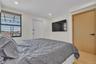 Wood-finish flooring, recessed lighting, solid-core light wood door with matte black hardware, and an expansive window with dark framing