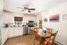 Kitchen featuring white cabinetry, stainless steel appliances,  quartz counters, a herringbone-pattern tile backsplash, and a central ceiling fan with