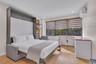Built-in dark-toned cabinetry with integrated shelving, wood-finish flooring, recessed lighting, and wall-mounted climate control unit