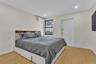 Room featuring neutral wall paint, wood-finish flooring, recessed lighting, a window with integrated shade, and a wall-mounted ductless climate contro